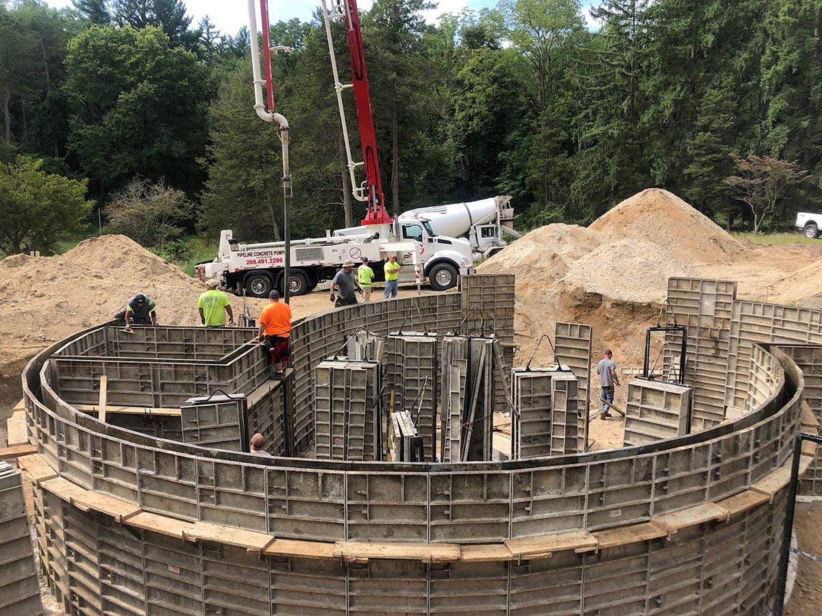 closer view of curved foundation and crew pouring cement