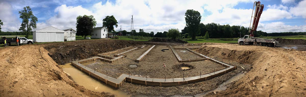 excavated job site with poured footings and trucks in background