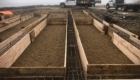 footings reinforced with rebar ready to be poured with concrete with trucks in the background