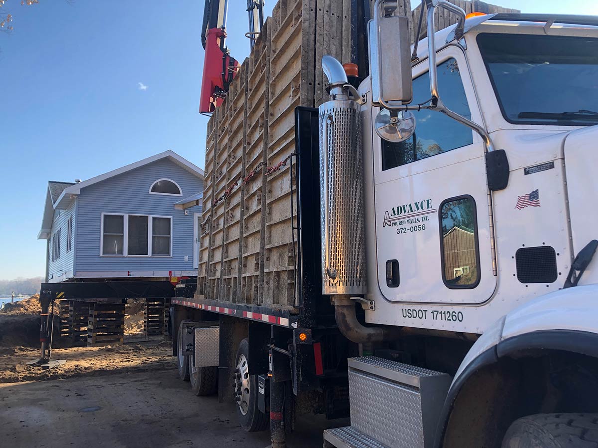 advance poured concrete truck with forms and moved house in background